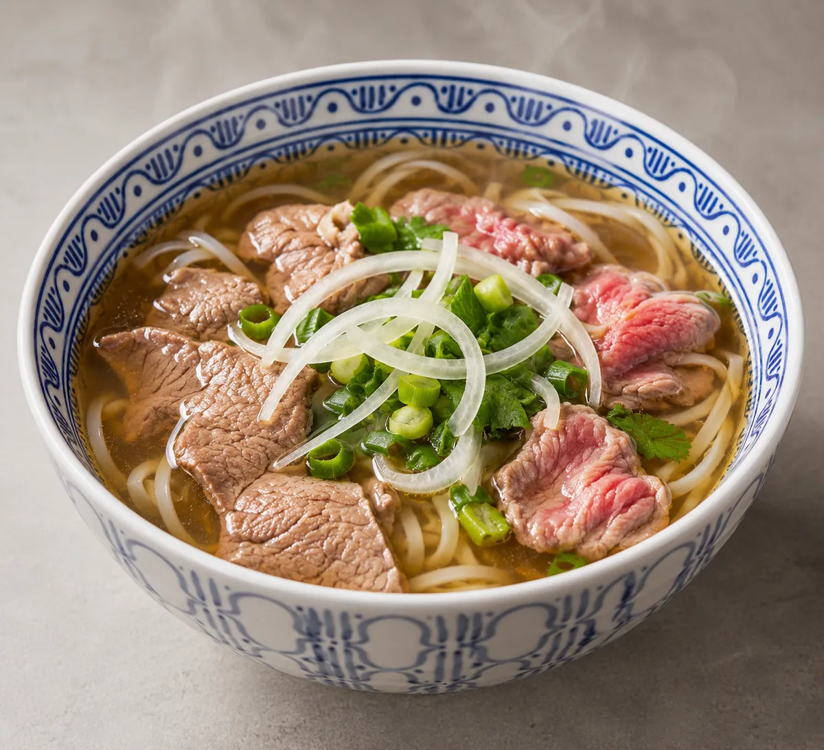 Bowl of traditional Vietnamese beef pho noodle soup with rare beef, rice noodles, onion and herbs