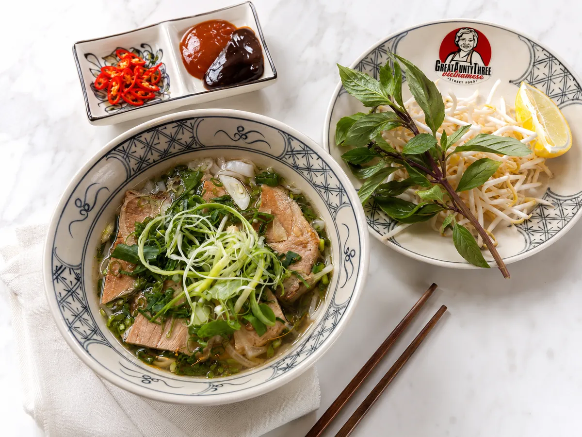Bowl of Vietnamese chicken pho with rice noodles, herbs and shredded chicken